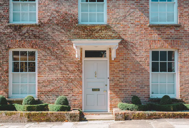 Composite Doors in Newcastle upon Tyne Pale blue front door with a fanlight on a red-brick house, illustrating composite doors for homes in Newcastle upon Tyne