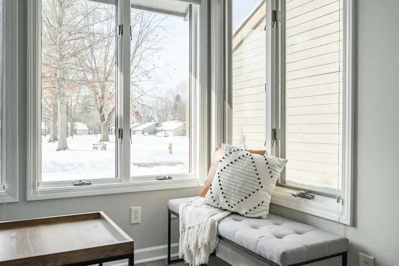 Tilt & Turn Windows in Newcastle upon Tyne Window seat with cushions beside a large white window, illustrating tilt & turn windows for homes in Newcastle upon Tyne